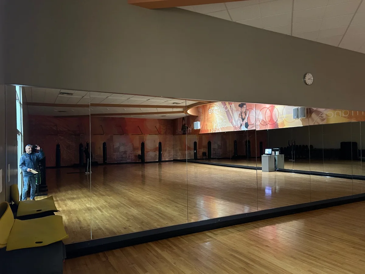 Long mirror wall above a dance studio wood floor.