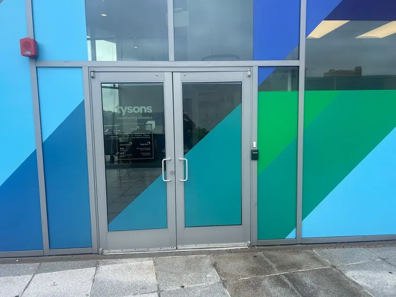 Double glass entry doors sit within a colorful storefront.