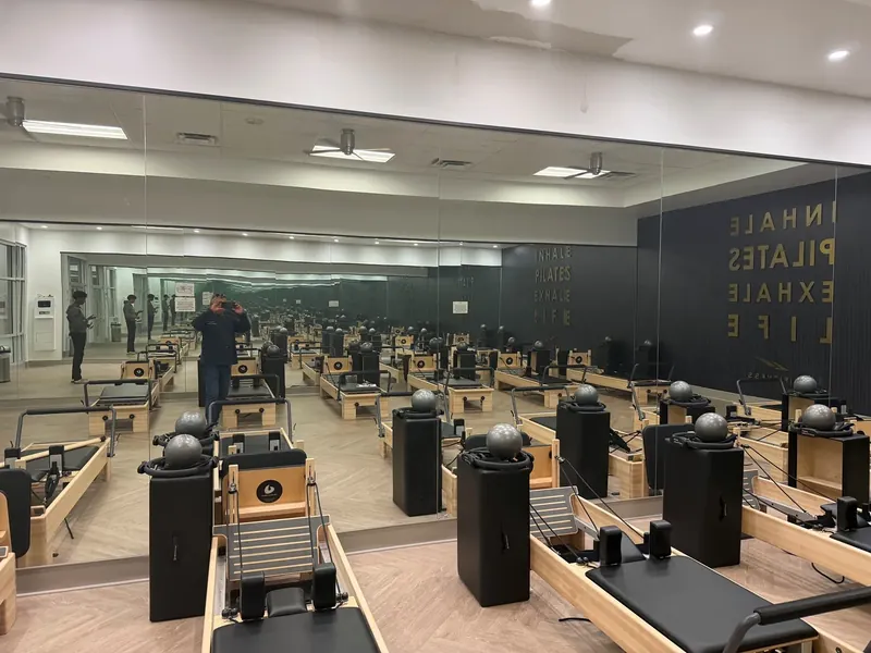 A wide view shows the Pilates studio reflected in wall mirrors.
