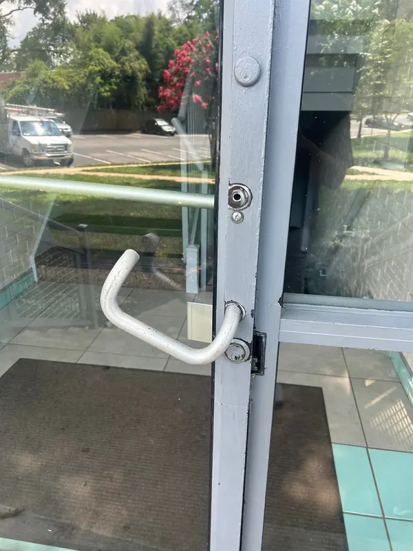 Bent pull hardware and visible damage near the lock on a glass entry door.