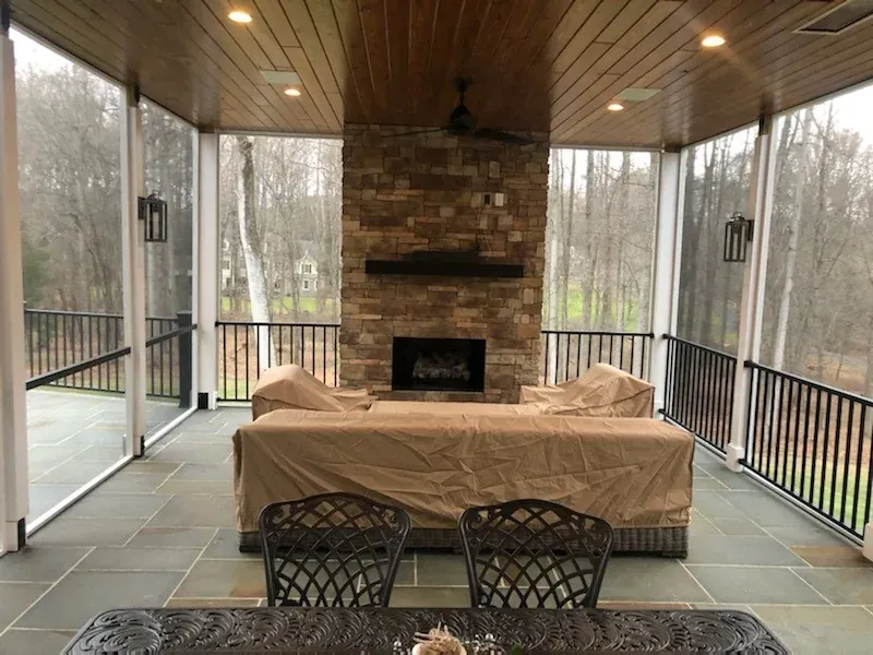 Screened porch interior with a stone fireplace.