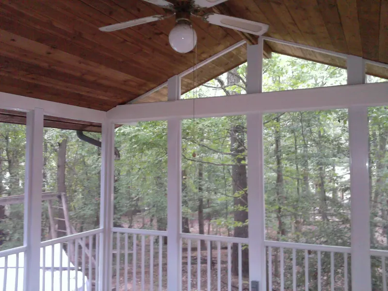 Porch interior with a wood cathedral ceiling and ceiling fan.