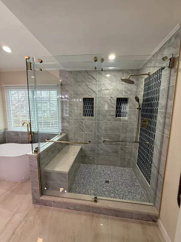 Front view of the corner shower enclosure with gold-tone hardware beside a freestanding bathtub.