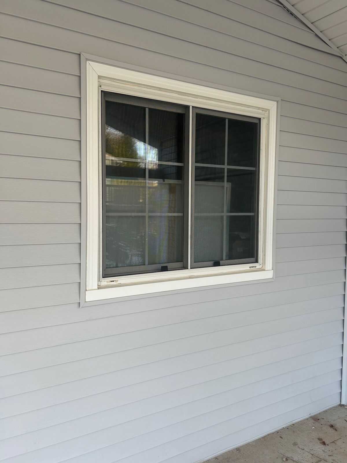 A white two-panel window set in a siding-clad wall