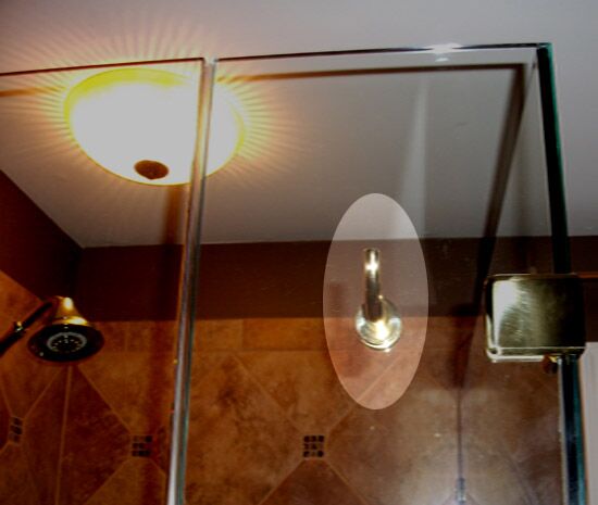 A robe hook mounted through a frameless shower glass panel