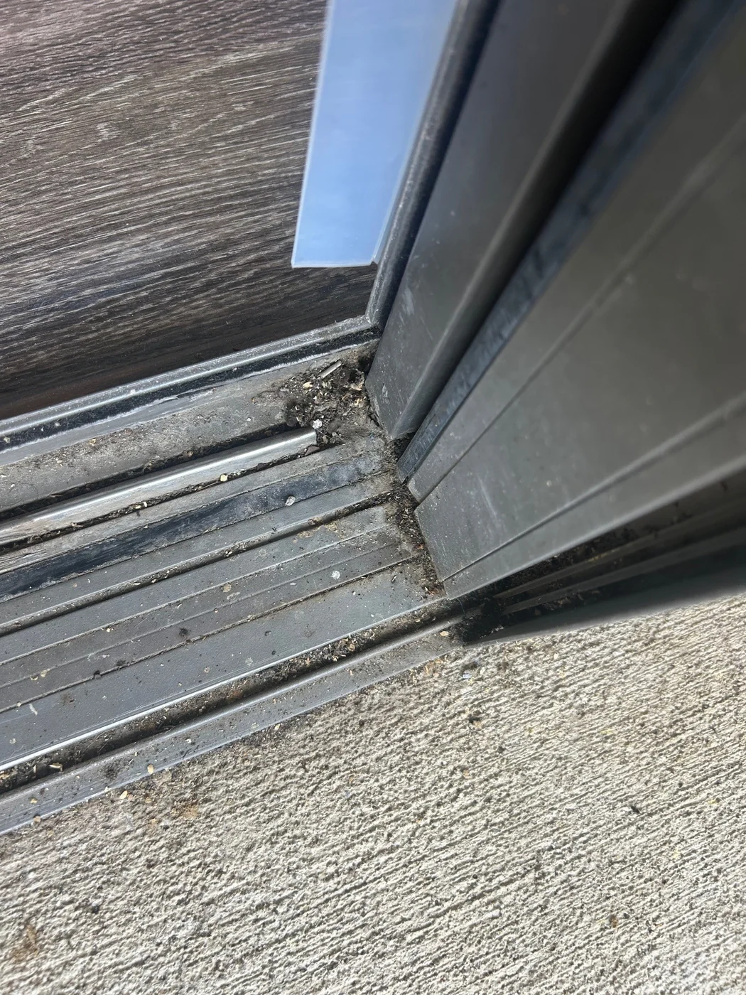 A sliding patio-door threshold with debris in the lower track