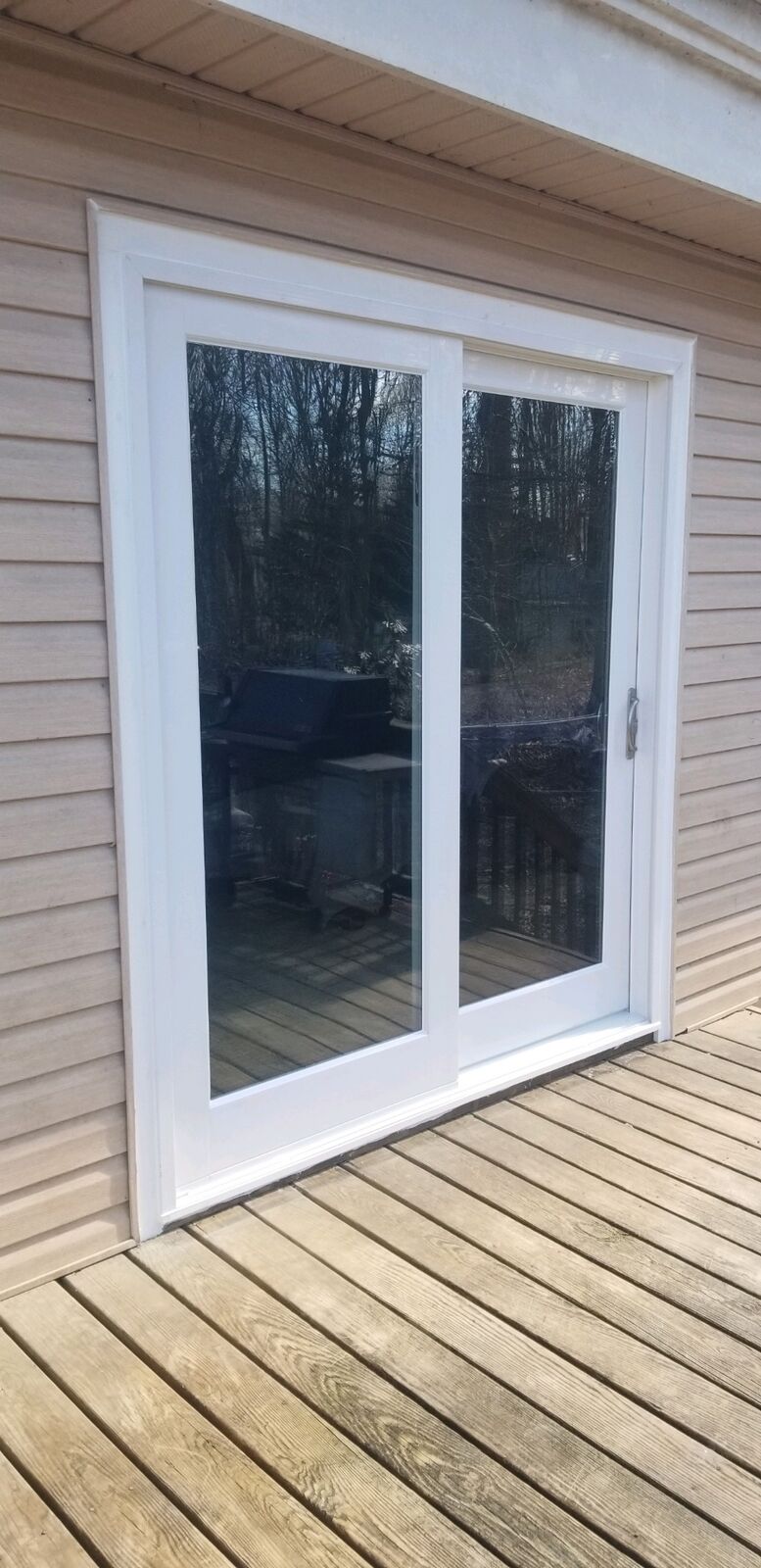 A white sliding patio door viewed from a wooden deck