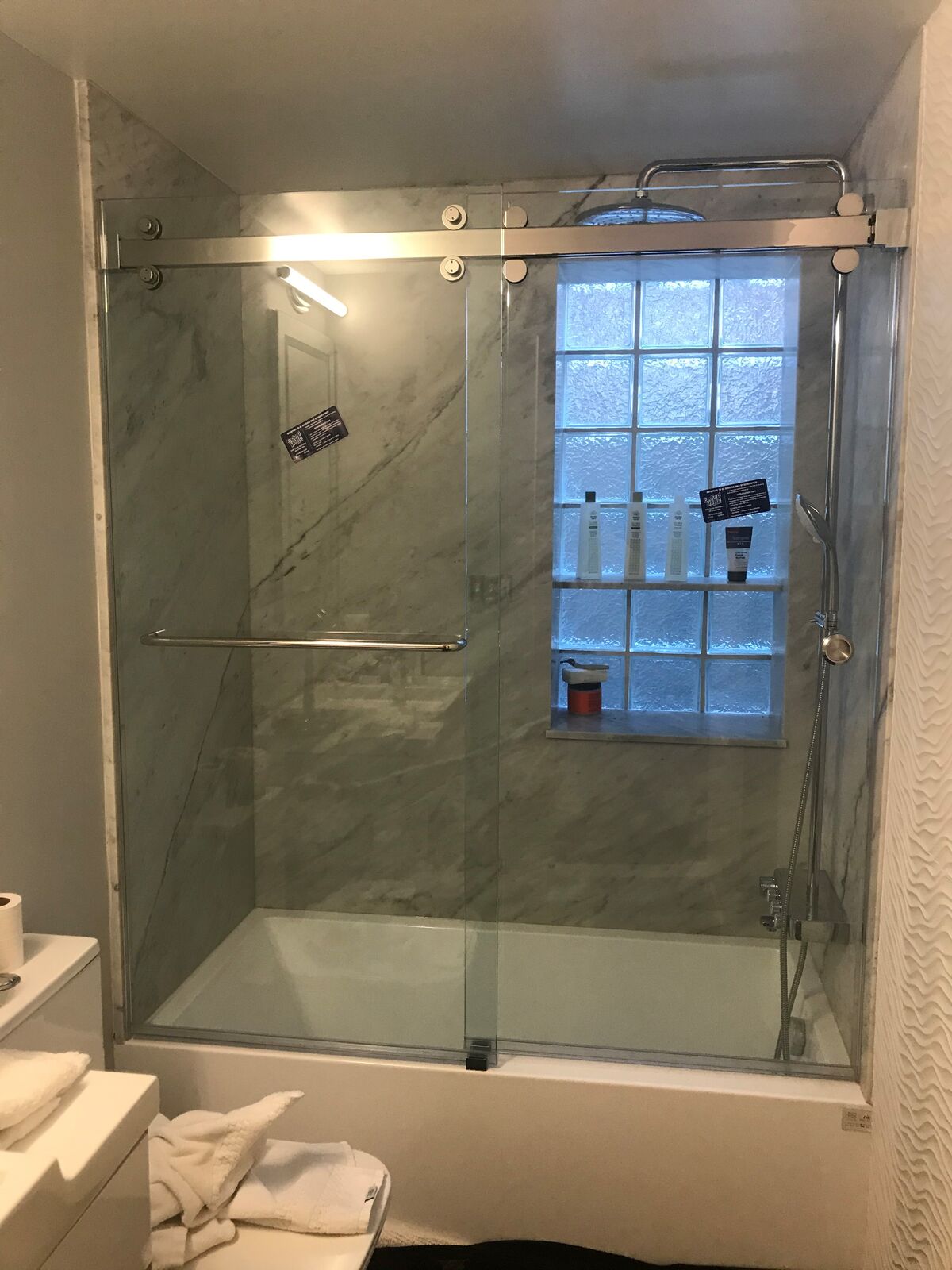 Sliding glass tub doors on a top rail with a glass-block window inside the tub area