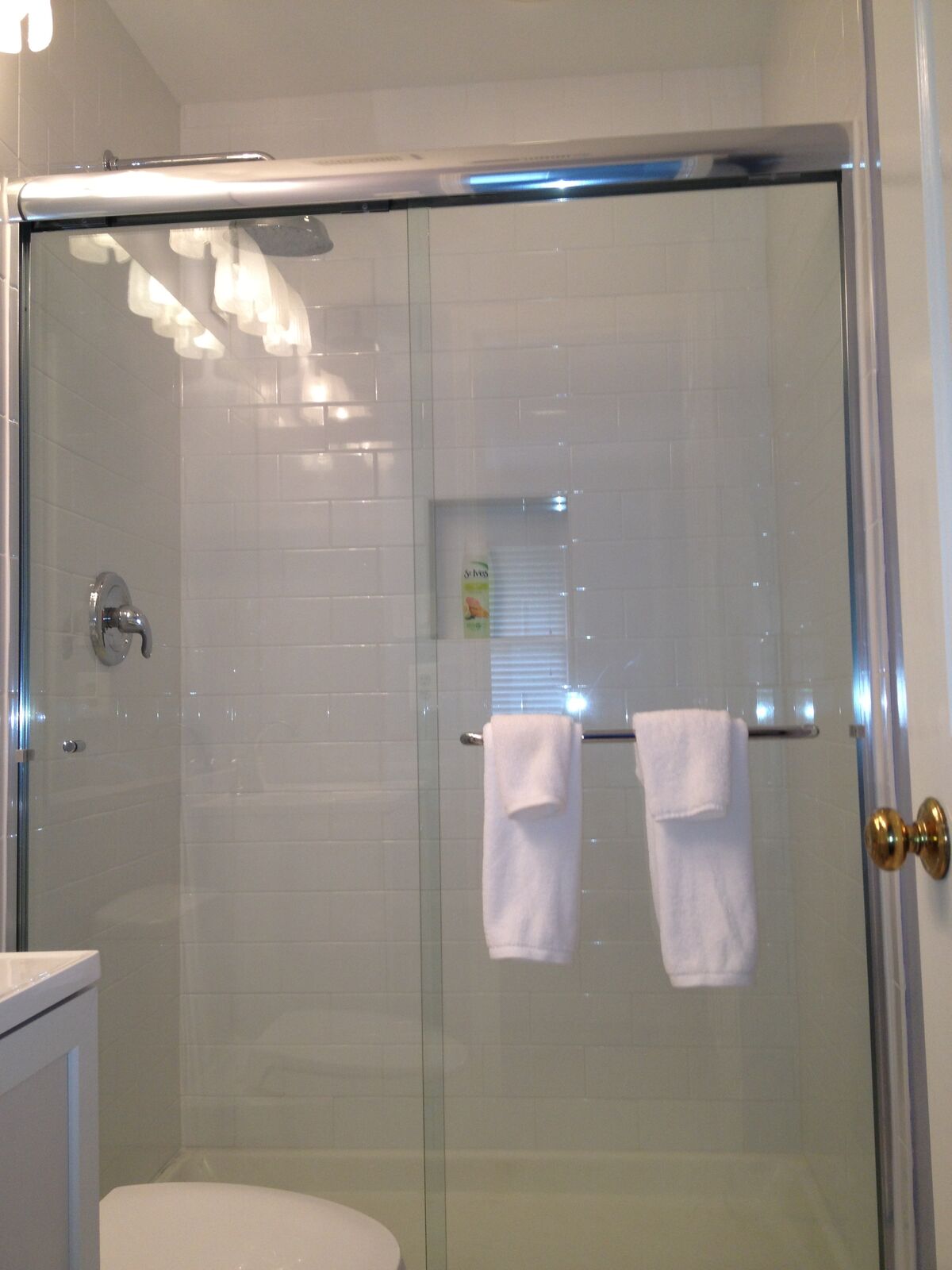 Sliding tub doors with a framed top track and towel bars holding white towels