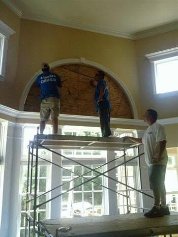AS&G technicians on scaffolding replacing glass in a large arched window