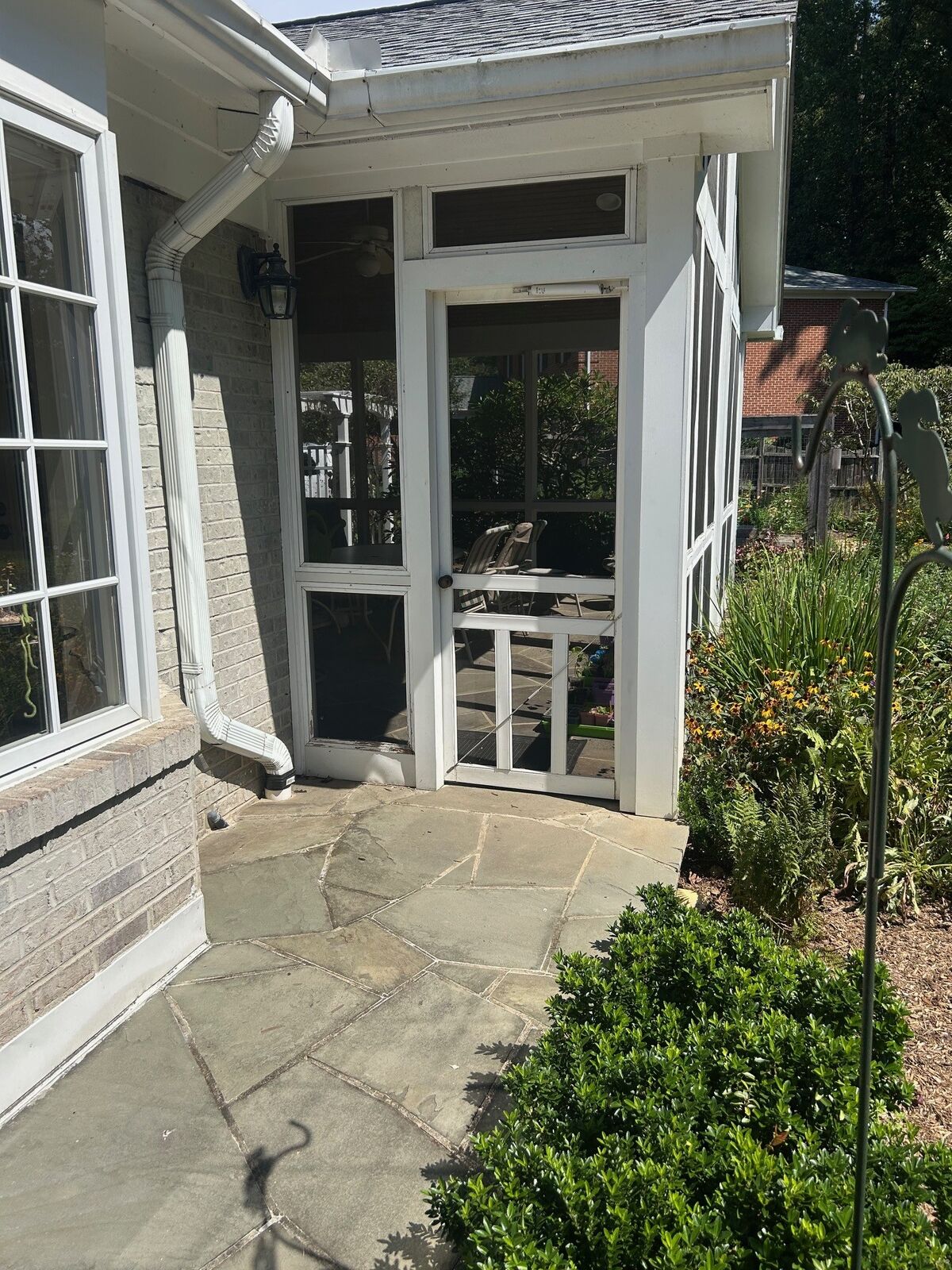 A screened porch entry door opening onto a stone patio