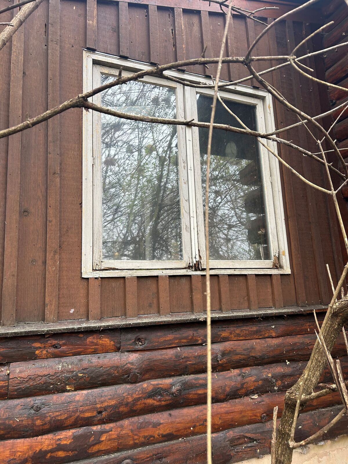 Older white-painted wood windows on a rustic log-and-board exterior